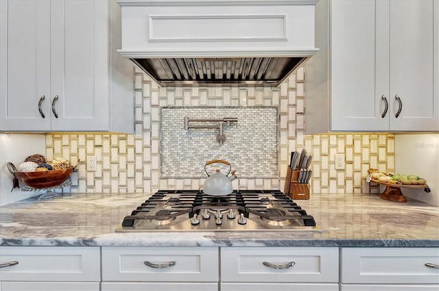 kitchen with tasteful backsplash, white cabinetry, custom exhaust hood, and stainless steel gas cooktop