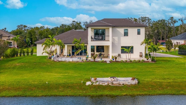 back of house featuring a lawn, a patio area, a balcony, and a water view