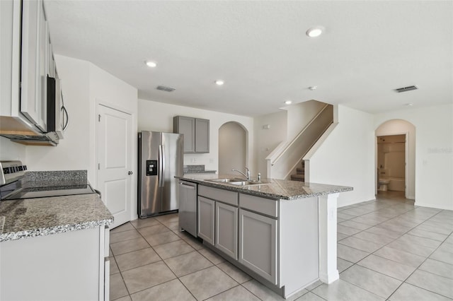 kitchen featuring a kitchen island with sink, sink, gray cabinets, light tile patterned floors, and stainless steel appliances