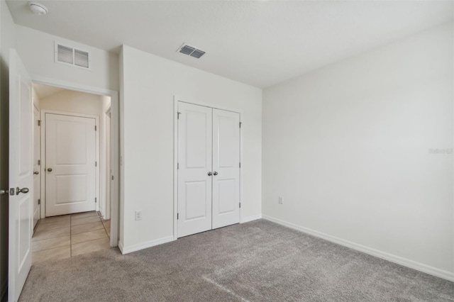 unfurnished bedroom featuring light carpet and a closet