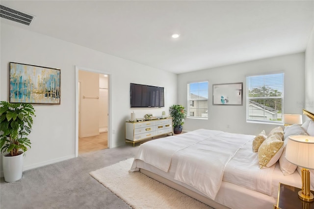 bedroom featuring light carpet and connected bathroom