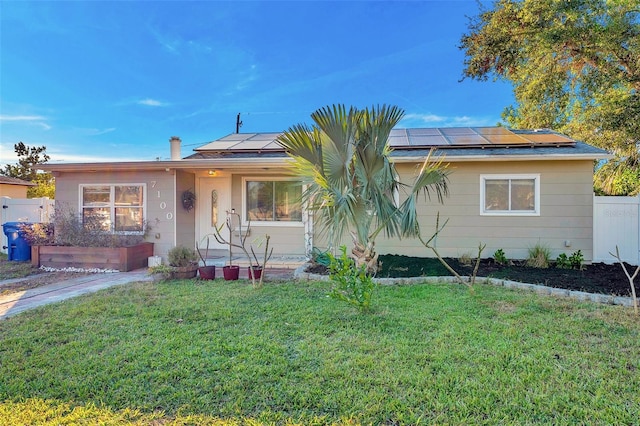 view of front of property featuring solar panels and a front yard