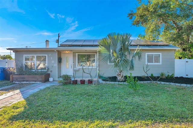 ranch-style home featuring solar panels and a front lawn