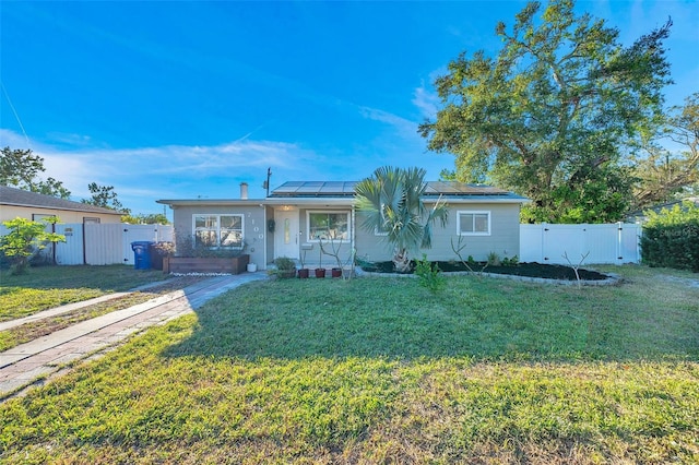 ranch-style house featuring a front yard, solar panels, and covered porch