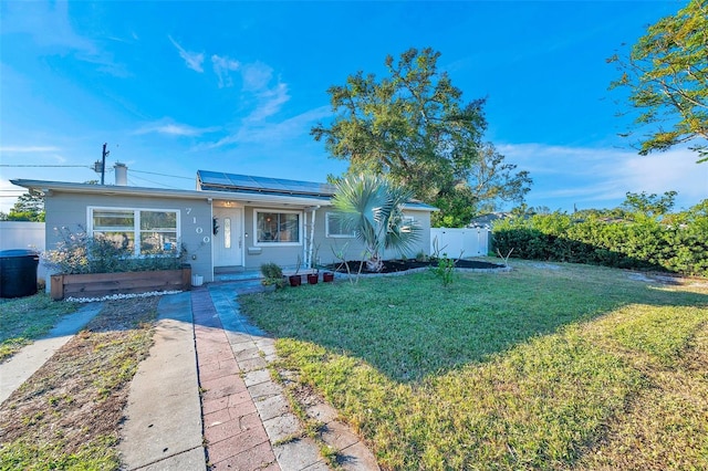 single story home featuring solar panels and a front yard