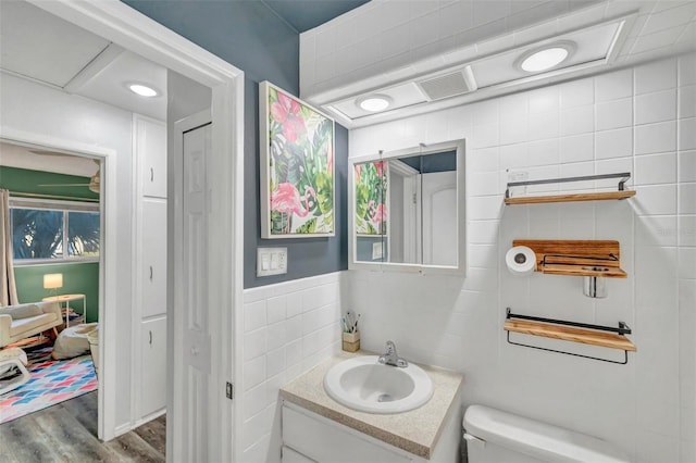 bathroom featuring hardwood / wood-style floors, vanity, toilet, and tile walls