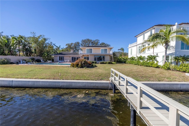 view of dock with a water view, a yard, and a fenced in pool