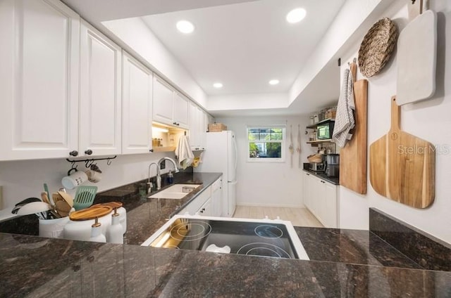 kitchen featuring sink, light hardwood / wood-style flooring, range, white fridge, and white cabinetry