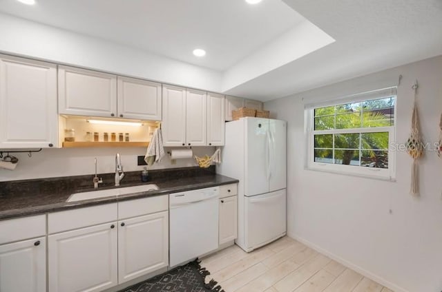 kitchen with white cabinetry, sink, light hardwood / wood-style floors, and white appliances