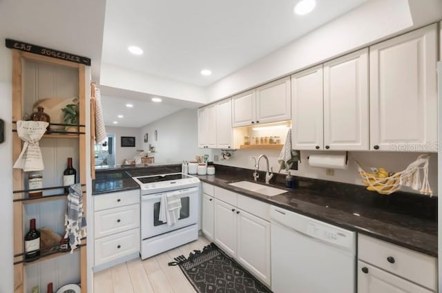 kitchen featuring dark stone countertops, sink, white cabinets, and white appliances