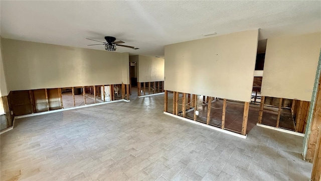 empty room with ceiling fan and a textured ceiling