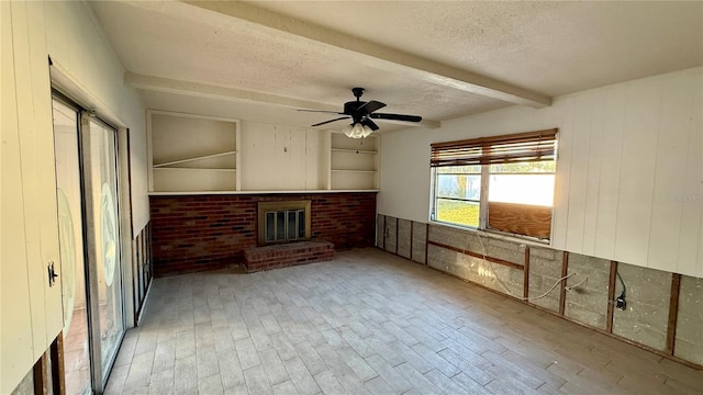 interior space featuring ceiling fan, a brick fireplace, wood-type flooring, a textured ceiling, and wooden walls