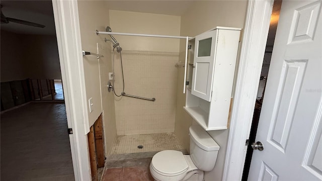 bathroom featuring tile patterned floors, a tile shower, and toilet