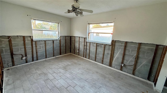 spare room with ceiling fan, a textured ceiling, and a wealth of natural light