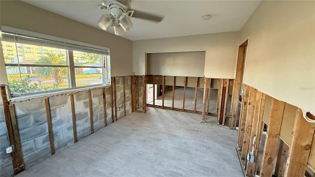 unfurnished room featuring ceiling fan and wood walls