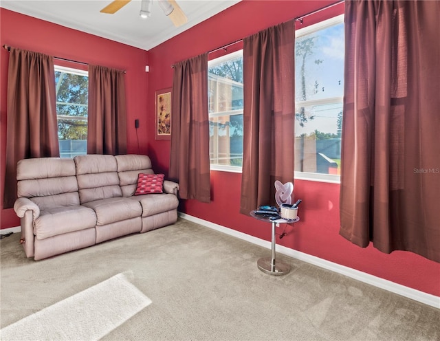 carpeted living area with baseboards, a ceiling fan, and a healthy amount of sunlight