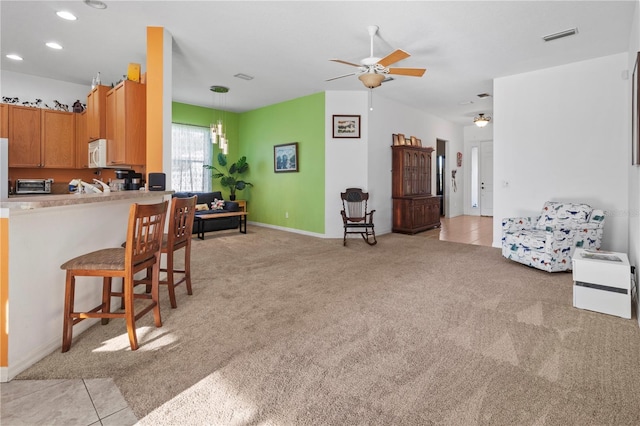 kitchen featuring white microwave, light carpet, visible vents, light countertops, and decorative light fixtures