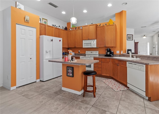 kitchen featuring white appliances, visible vents, a kitchen island, a kitchen bar, and a sink