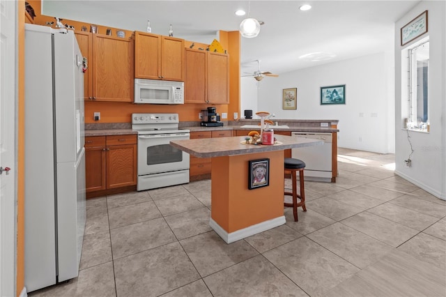 kitchen with white appliances, a center island, light countertops, a kitchen bar, and a sink