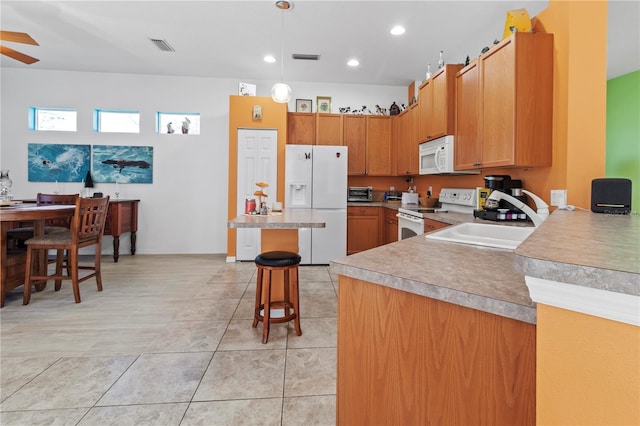 kitchen featuring white appliances, a sink, a kitchen breakfast bar, light countertops, and decorative light fixtures