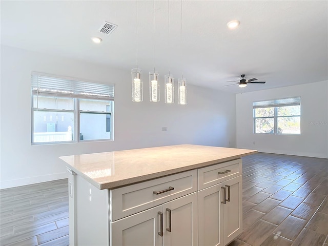 kitchen featuring ceiling fan, a center island, dark wood-type flooring, and decorative light fixtures