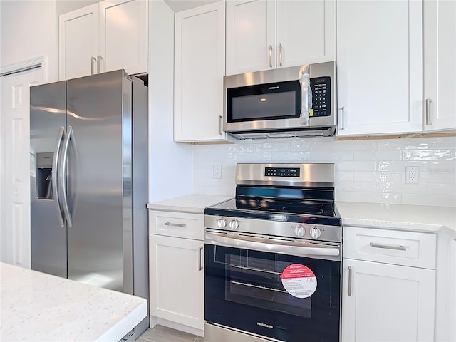 kitchen featuring white cabinets, decorative backsplash, light stone countertops, and appliances with stainless steel finishes