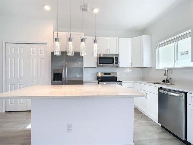 kitchen with pendant lighting, a center island, white cabinetry, and stainless steel appliances