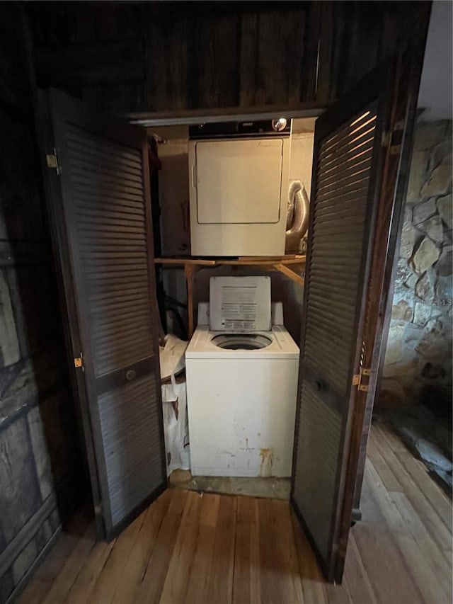 laundry room with stacked washer and dryer and hardwood / wood-style flooring