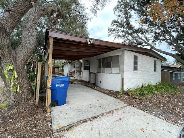 exterior space featuring a carport, concrete driveway, and fence