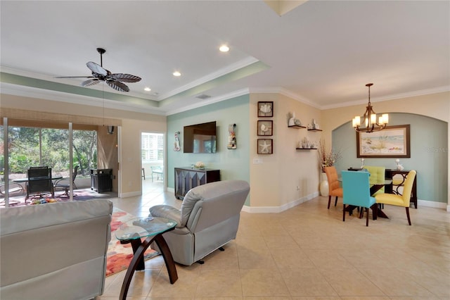 living room with ceiling fan with notable chandelier, a raised ceiling, ornamental molding, and light tile patterned floors