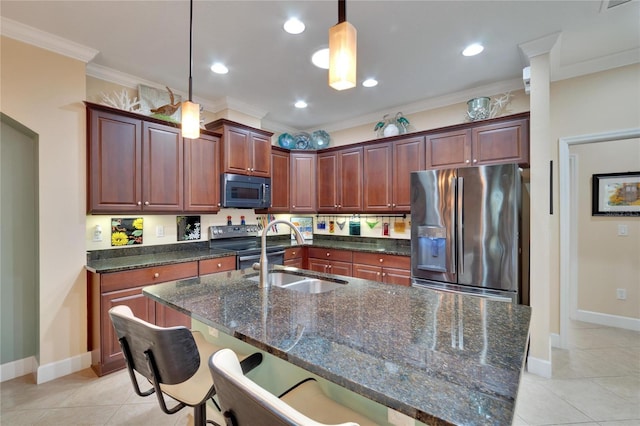 kitchen with pendant lighting, a kitchen island with sink, sink, and appliances with stainless steel finishes