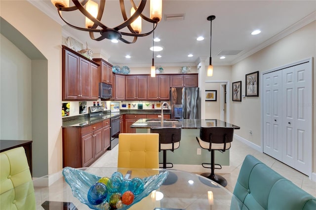 kitchen featuring appliances with stainless steel finishes, sink, pendant lighting, an inviting chandelier, and an island with sink