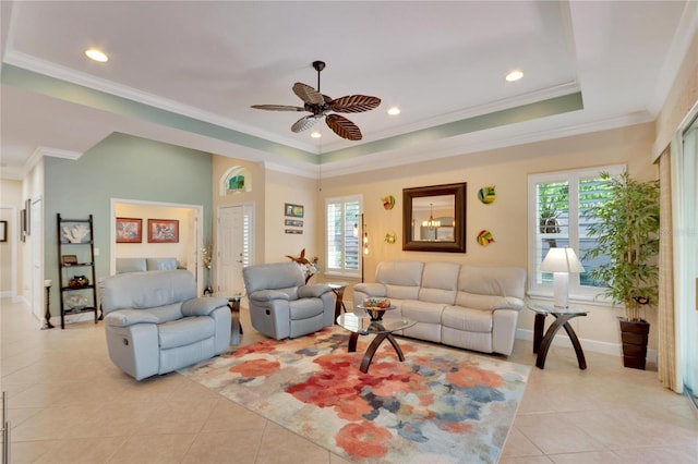 living room featuring a raised ceiling, ceiling fan, light tile patterned floors, and ornamental molding