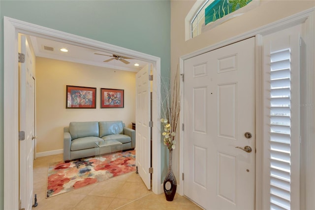 tiled entryway featuring ceiling fan and crown molding