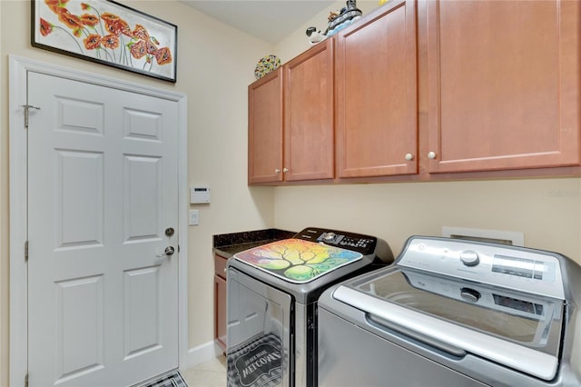 clothes washing area with cabinets, washer and dryer, and light tile patterned flooring