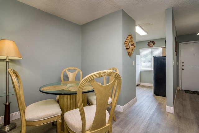 dining area featuring light hardwood / wood-style floors and a textured ceiling