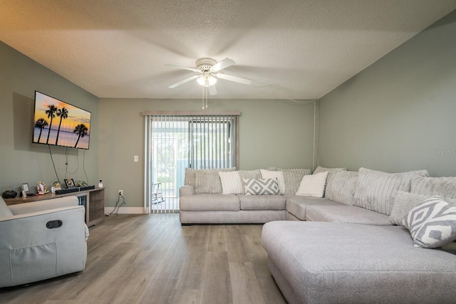 living room with ceiling fan, a textured ceiling, and light wood-type flooring