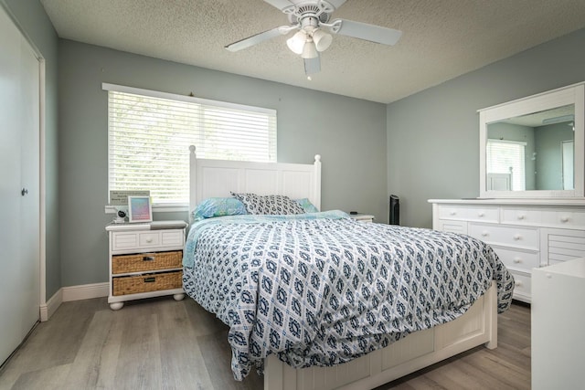 bedroom featuring light wood-type flooring, a textured ceiling, a closet, and ceiling fan