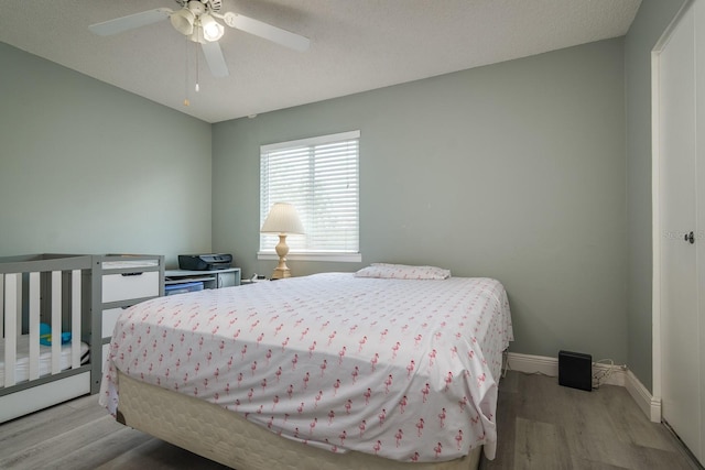 bedroom featuring a textured ceiling, light wood-type flooring, and ceiling fan