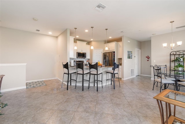 kitchen featuring pendant lighting, a notable chandelier, white cabinetry, and appliances with stainless steel finishes