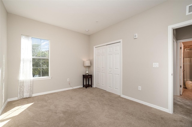 unfurnished bedroom featuring light carpet and a closet