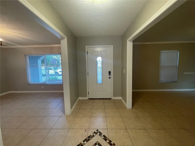 entrance foyer with light tile patterned floors, a textured ceiling, and ornamental molding