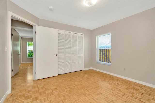 unfurnished bedroom with a closet, a textured ceiling, and light parquet floors