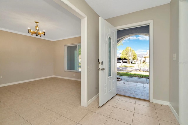 foyer featuring an inviting chandelier, ornamental molding, a healthy amount of sunlight, and light tile patterned flooring