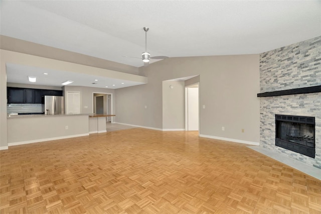 unfurnished living room featuring ceiling fan, vaulted ceiling, light parquet flooring, and a fireplace