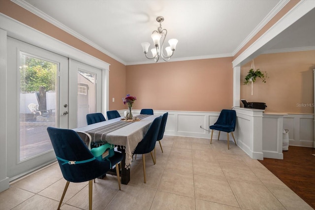 dining area featuring french doors, light hardwood / wood-style floors, an inviting chandelier, and ornamental molding