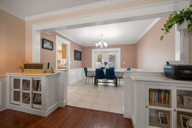 dining room with french doors, hardwood / wood-style flooring, crown molding, and a notable chandelier