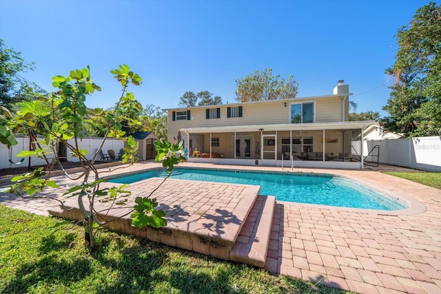 view of swimming pool with a patio, a storage shed, and a sunroom