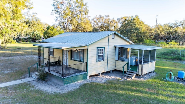 rear view of property featuring a lawn, a sunroom, and a porch