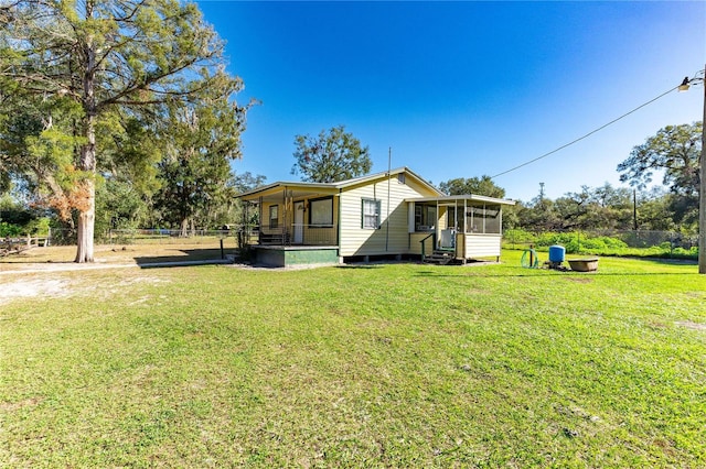 rear view of property with a lawn and a sunroom